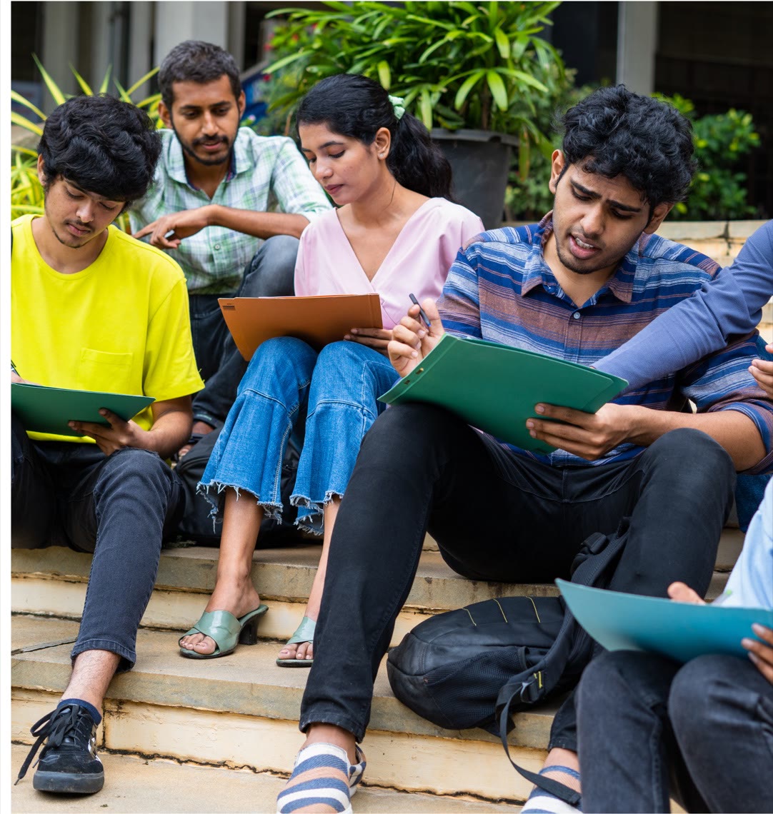 Students sitting together on campus steps, comparing notes